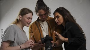 Model and production team in the studio. Photographer female model and girl assistant talking checking pics on camera together