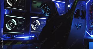 A hacker wearing a mask to cover his face is using computer to hack data to get ransom from victims.