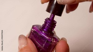 Woman's hand opens a bottle of nail polish, Advertisement of gel nail polish in bright color. Slowly dripping drops of gel nail polish nail polish .
