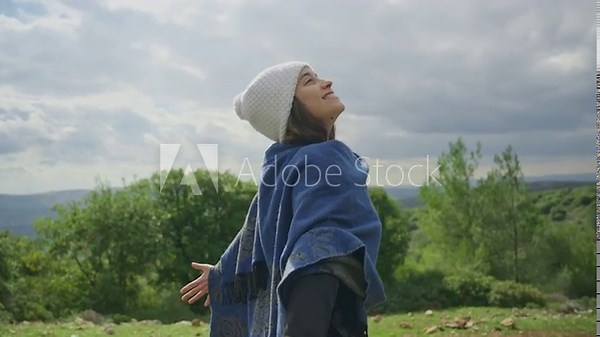 Female hippie or bohemian smiling and joyful feeling connection to nature. Standing outdoors with her arms extended in spiritual or meditative state ritual. Free spirit and carefree. Thankful to earth