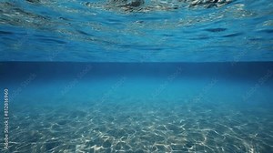 Underwater world in the blue sea. The background is an underwater view showing the seabed and sea surface illuminated by sunlight with water ripples. 4K