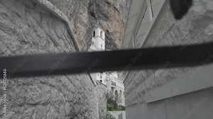 Ostrog monastery in Montenegro seen from the gap in the iron fence. The unique monastery in the rock. the Monastery of Ostrog dedicated to Saint Basil of Ostrog. 4K videos.