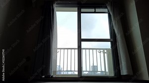 A skyscraper seen from the window of vacant studio apartment and curtains swaying in the wind. timelapse.