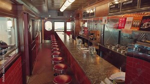 View into an empty nostalgic old fifties Diner with lots of signs and a bar and stools