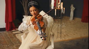Beautiful woman professional musician plays a wooden on the violin. Pretty face girl violinist musician plays at event ball. lady in white vintage dress. creative hairstyle dark hair old style art 4k Stock Video