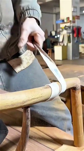 sanding wood chair frame carefully using long sandpaper strips to achieve smooth and even surfaces
