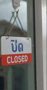 Person in apron a small business cafe or restaurant owner opening door shop and turning doorplate from "CLOSED" to "OPEN" (in English, Thai), business reopening and SME concepts vertical orientation.