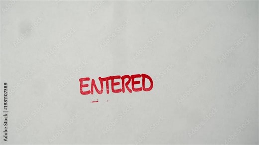 Rubber stamp prints entered text in red ink over empty white document during entry verification.