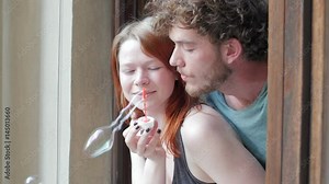 Girl and guy blowing bubbles out the window Stock Video