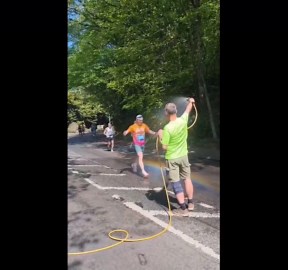 Man cools down Leeds Marathon runners with hose shower in West Yorkshire, England