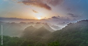 Time Lapse Dawn Over Cat Ba national Park. Morning fog and clouds fly among the karst cliffs of the Vietnamese reserve in the dawn soft light of the morning golden sun.