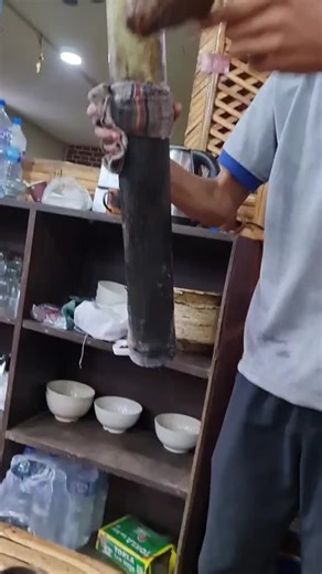 Pouring Traditional Bamboo Beverage in Rustic Setting