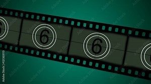 Old fashioned style countdown leader in a film strip moving over a green background.