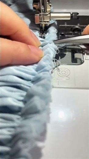sewing light blue ruffled fabric using a professional sewing machine for garment manufacturing