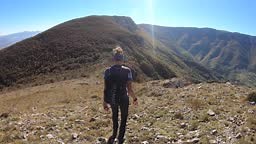 Women hiking mountain ridge, wearing sports equipment.