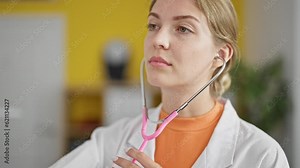 Young blonde woman doctor holding stethoscope examining at clinic