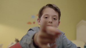Little boy changes pages with his finger on his cell phone or computer screen in his room. Front phone camera view. Future technology. Focused kid using invisible touchscreen. Touching the screen.