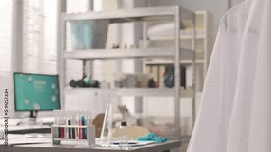 Overview of modern scientific laboratory interior with professional equipment, white lab coats and test tubes with different liquid substances on table