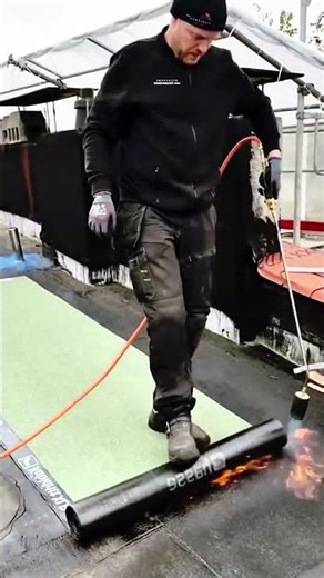 Worker uses propane torch to bond roof membrane
