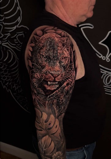 From old ink to a full transformation. This cover up tattoo turned an outdated upper arm piece into a powerful black and grey realism panther sleeve. The new design brings depth, contrast, and flow to the entire arm while completely reworking the original tattoo. Bold textures, detailed fur work, and strong composition create a piece that commands attention and gives the arm a whole new life. #TattooCoverUp #BeforeAndAfterTattoo #BlackAndGreyTattoo #RealismTattoo