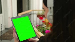 Business female in the cafe works with tablet pc video calls. Mobile working outside office. Young lady. View over shoulder at notepad. Close up woman using cell pad, garden. Green screen, texting