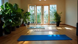 Camera slowly zooms in on a serene yoga studio for international yoga day, with mats, candles, and natural light