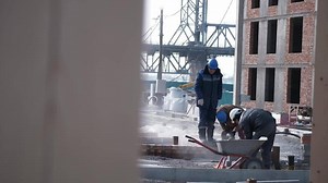 Download People in construction uniforms and safety helmets work on a construction site for free