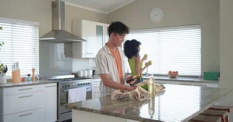 clip-4048521101-couple-entering-kitchen-unloading-net-bags-on