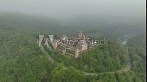 High drone footage of Bourscheid medieval Castle on a foggy day in north-eastern Luxembourg