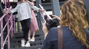 Photo session of couple in city. Action. Female photographer holds photo session for couple in love in city. Side view of photo shoot. Backstage photo sessions