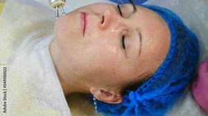 Modern beauty clinic with hardware cosmetology. Top view. Middle aged woman getting rf lifting skincare facial procedure. skin rejuvenation. Female client getting face rf-lifting treatment. 4 k video