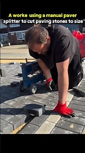 A worker using a manual paver splitter to cut paving stones to size