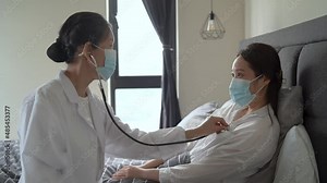 Female doctor using stethoscope to examine patient.