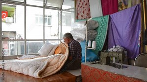 old man sewing a quilt with his hands