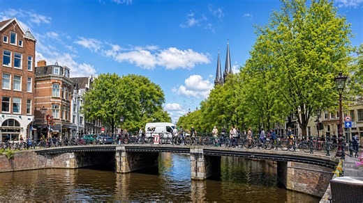 Amsterdam canal scene with bikes, people and city energy