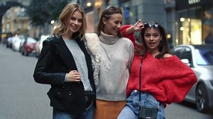 Three girls are walking down the street talking about something