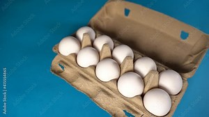 Farm raw, fresh white chicken egg in an egg box on a blue background. Eggs in carton. Eggs in the basket. Concept: a fresh egg for the morning breakfast.