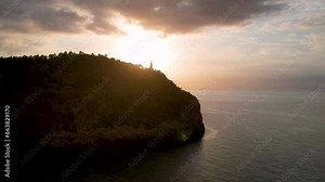 4K Aerial Drone video of popular summer destination, sunset over the cliffs with a lighthouse and a huge port of boats anchored at golden hour with seagulls flying. Port de Soller, Mallorca