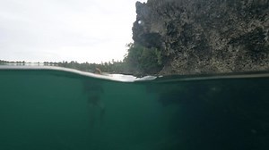 Underwater view of a woman swimming and snorkeling in a clear natural cave pool.