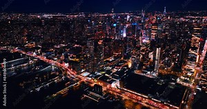 Hundreds of car stand on the highway at the waterfront of the East River at night. Luminous panorama of New York, the USA from top.