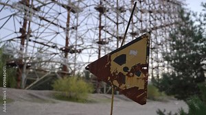 Abandoned radiation sign with Duga horizon radar systems on background in Chernobyl, Ukraine