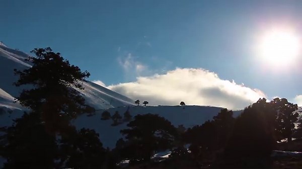 Winter clouds move slowly over snow-covered mountains