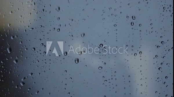 Raindrops on a window pane during an autumn storm, with one droplet sliding down the glass surface. 4K.