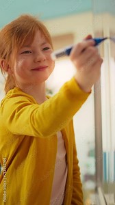Vertical Screen: Girl Solving an Arithmetic Equation that a Teacher Gave Her. Portrait of a Happy Elementary School Pupil Studying Hard, Writing a Correct Answer on a Whiteboard During a Math Class