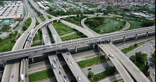 4K. Aerial view of road interchange of highway intersection with busy urban traffic speeding on the road. Junction network of transportation taken by drone.