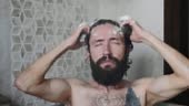Young bearded man is washing head in a shower at home, close-up. Male...