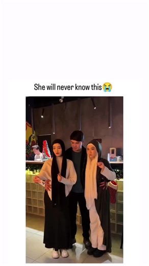 LOLAndLearn on Instagram: "This Instagram reel features a short video of two women and a disguised man in hijabs posing for a group selfie in a festive cafe, with a comedic reveal as the man removes his hood, overlaid with trollface memes and Spanish song lyrics about heartbreak, captioned"She will never know this" Posted on 4 January 2026 by @IAKSSaviour, a meme enthusiast with a bio "life is a meme", it amassed over 12,000 likes and 3 million views in under a day, highlighting viral appeal of