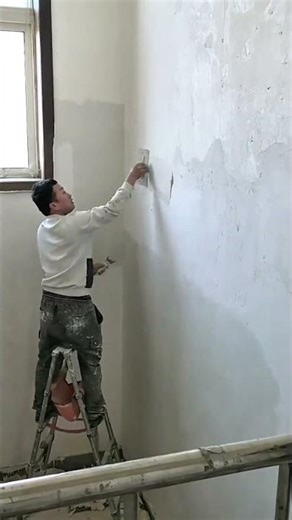 smoothing white plaster on a wall surface using a trowel to create a fine finish for renovation