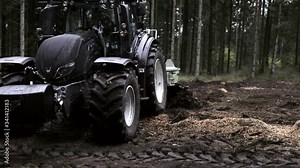 Scarifier drive by the camera while working the soil in a forest.