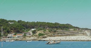View from the boat of the Tremiti Islands coastline with its crystal clear sea. In the foreground the flag of Italy fixed on board the boat. Apulia - Italy